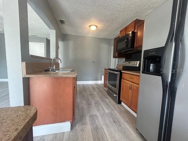 A kitchen features wood cabinets, stainless steel appliances, and light-colored wood-look flooring — 1025 25TH STREET, ORLANDO, FL