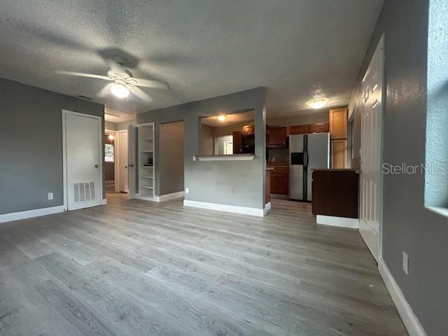 A living room with light wood-look flooring leads to an open kitchen with dark cabinets — 1025 25TH STREET, ORLANDO, FL