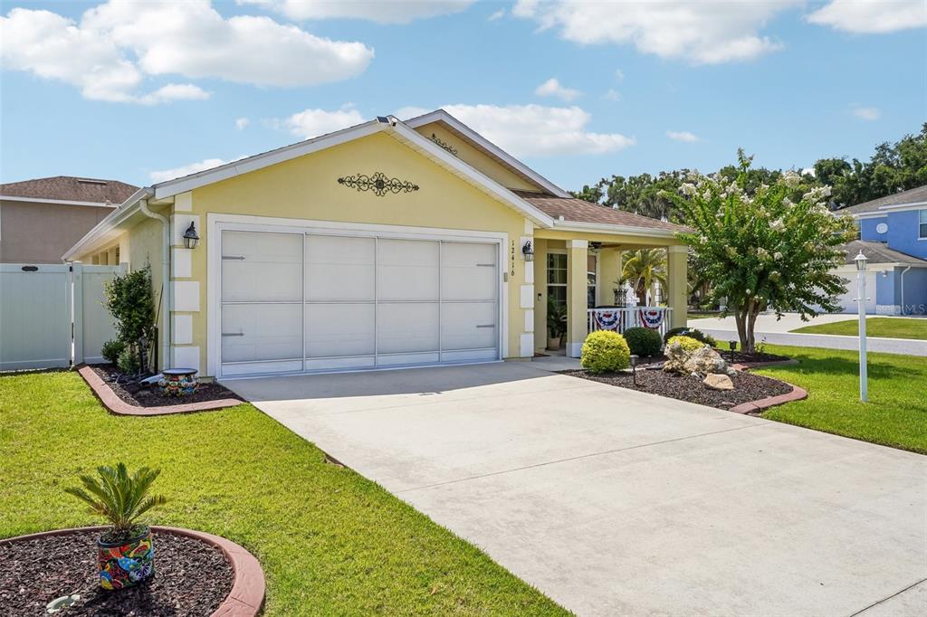 A yellow single-story house with a two-car garage and a front porch — 12416 NE 48TH LOOP, OXFORD, FL