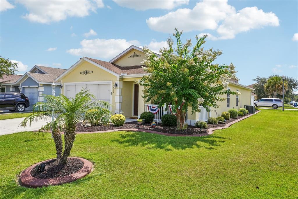 A yellow single-story house with a palm tree and a blooming tree in the front yard — 12416 NE 48TH LOOP, OXFORD, FL