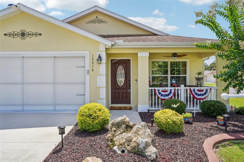 A single-story house with yellow stucco siding, a brown front door, and a covered porch — 12416 NE 48TH LOOP, OXFORD, FL