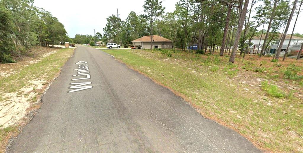 A paved road runs through a wooded residential area with a house in the distance — 2078 W LINDEN DRIVE, CITRUS SPRINGS, FL
