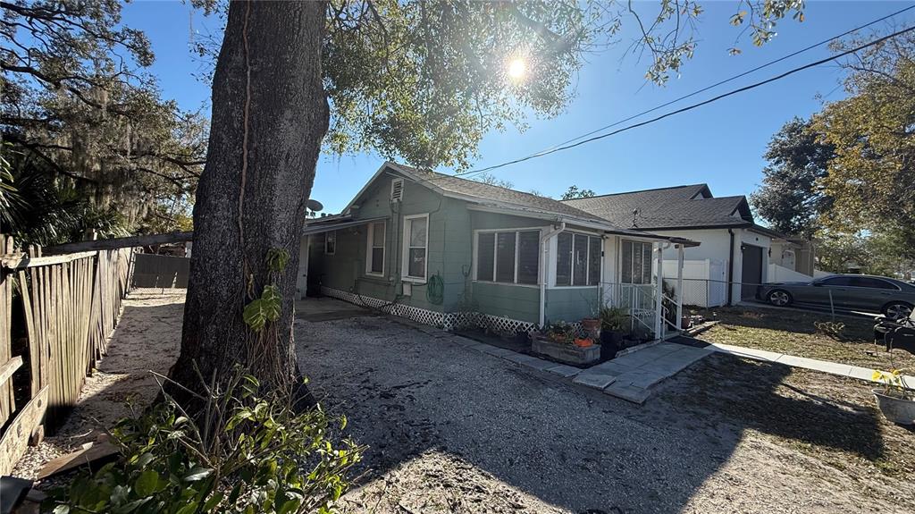 A green, single-story house with a gravel driveway and a large tree in the foreground — 2504 W SOUTH AVENUE, TAMPA, FL