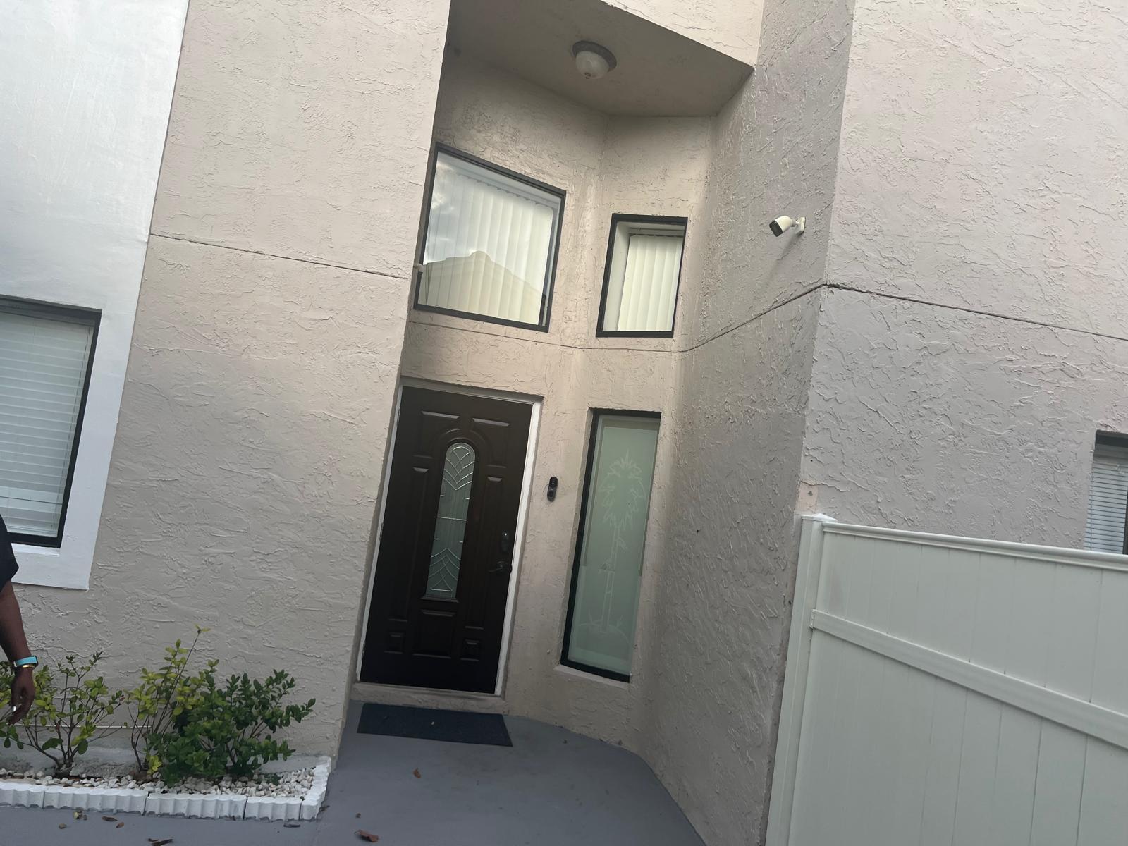 The exterior of a home features a dark brown front door, windows, and stucco walls — 5765 Strawberry Lakes Circle, Lake Worth FL 33463, LAKE WORTH, FL