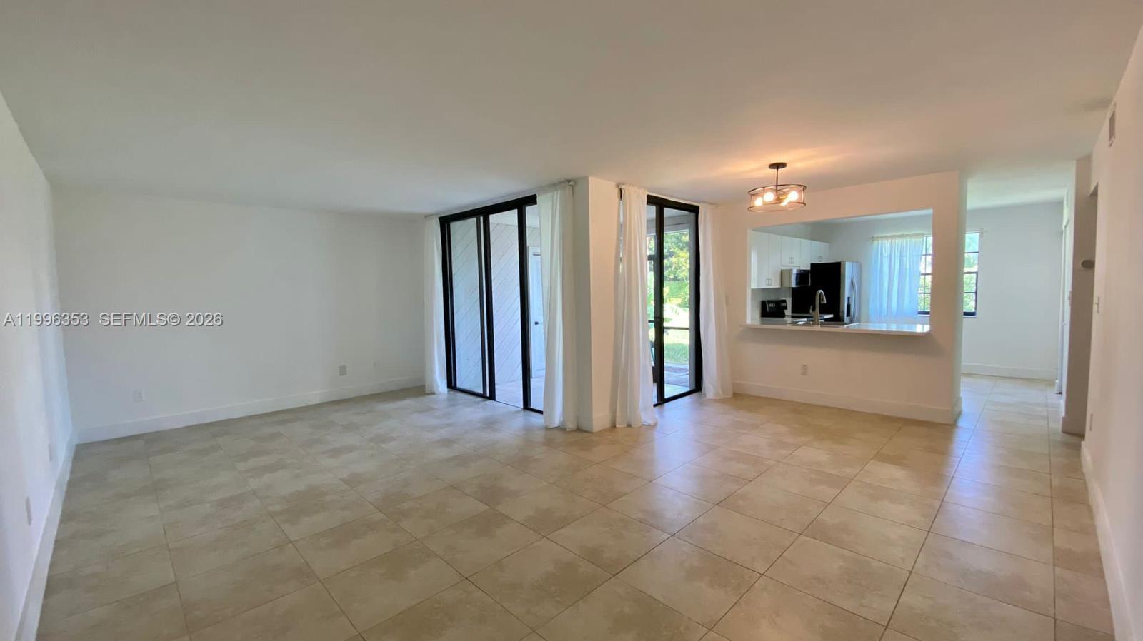 An open-concept living area features light-colored tile floors, white walls, and a pass-through kitchen — 3552 Magellan Cir # 126, Aventura FL 33180, AVENTURA, FL