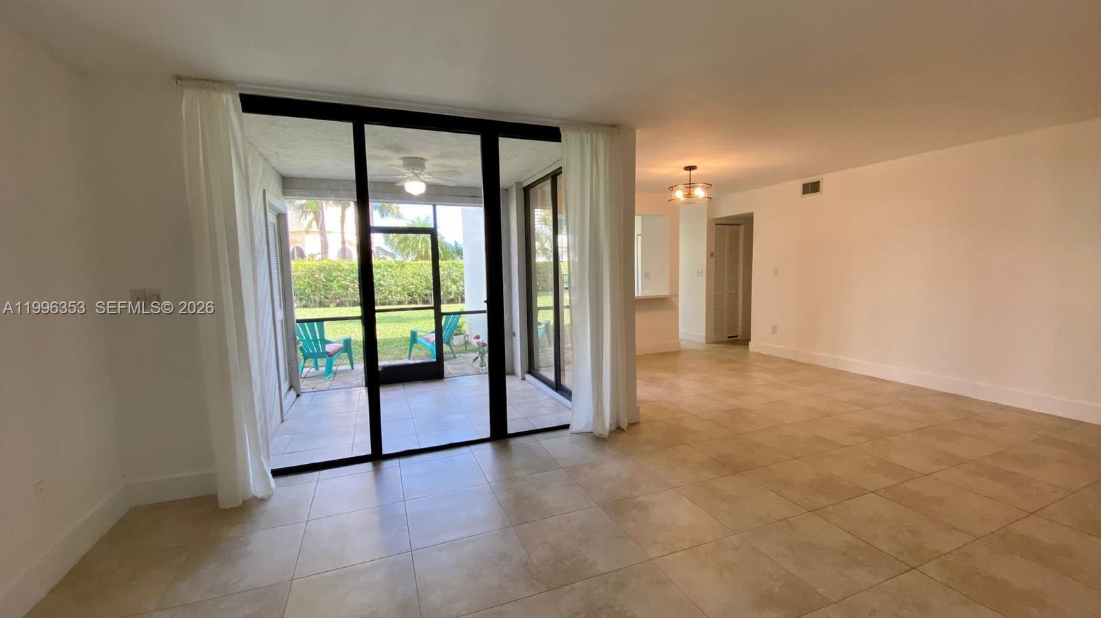 An interior view shows a tiled living area with a screened-in patio and white walls — 3552 Magellan Cir # 126, Aventura FL 33180, AVENTURA, FL