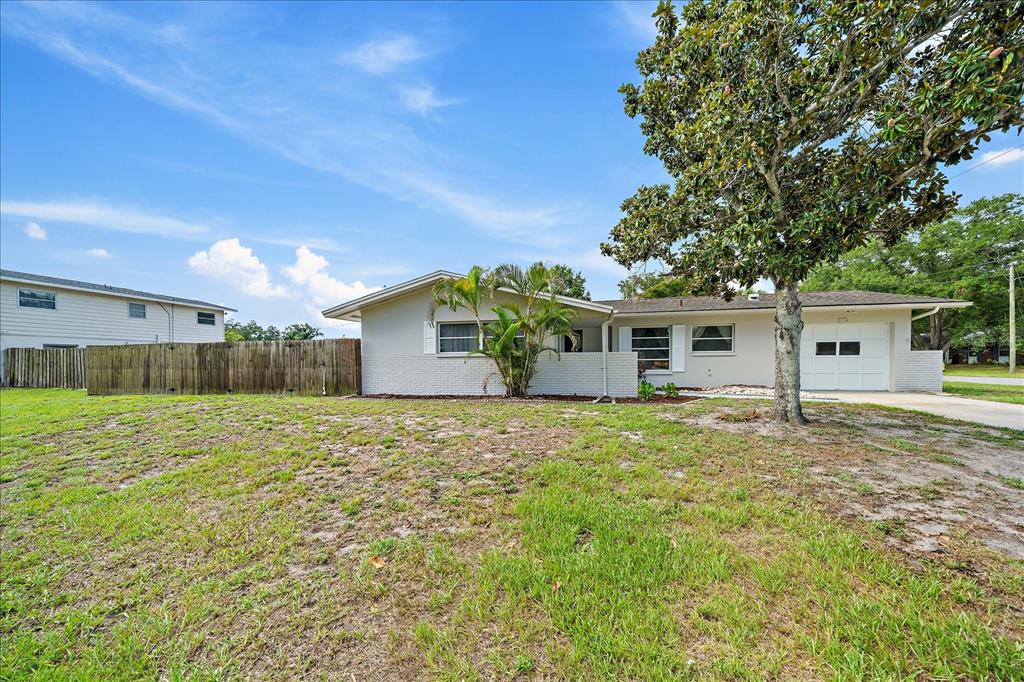 A single-story house with a light-colored brick exterior, a garage, and a large tree — 1210 DORIS DRIVE, SARASOTA, FL