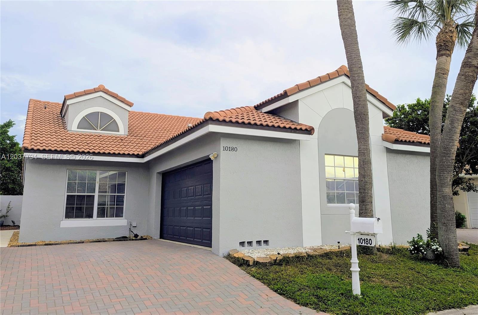 A single-story house with a gray stucco exterior, a tiled roof, and a paved driveway — 10180 Fanfare Dr # 10180, Boca Raton FL 33428, BOCA RATON, FL