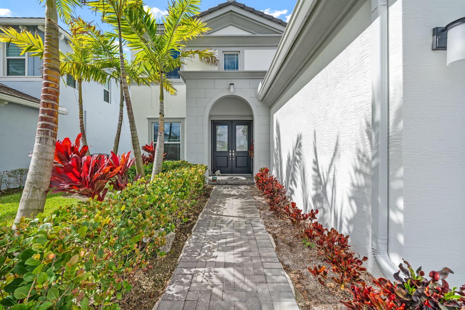 A paved walkway leads to the dark double front doors of a white stucco house — 5449 Empire Drive, Westlake FL 33470, WESTLAKE, FL