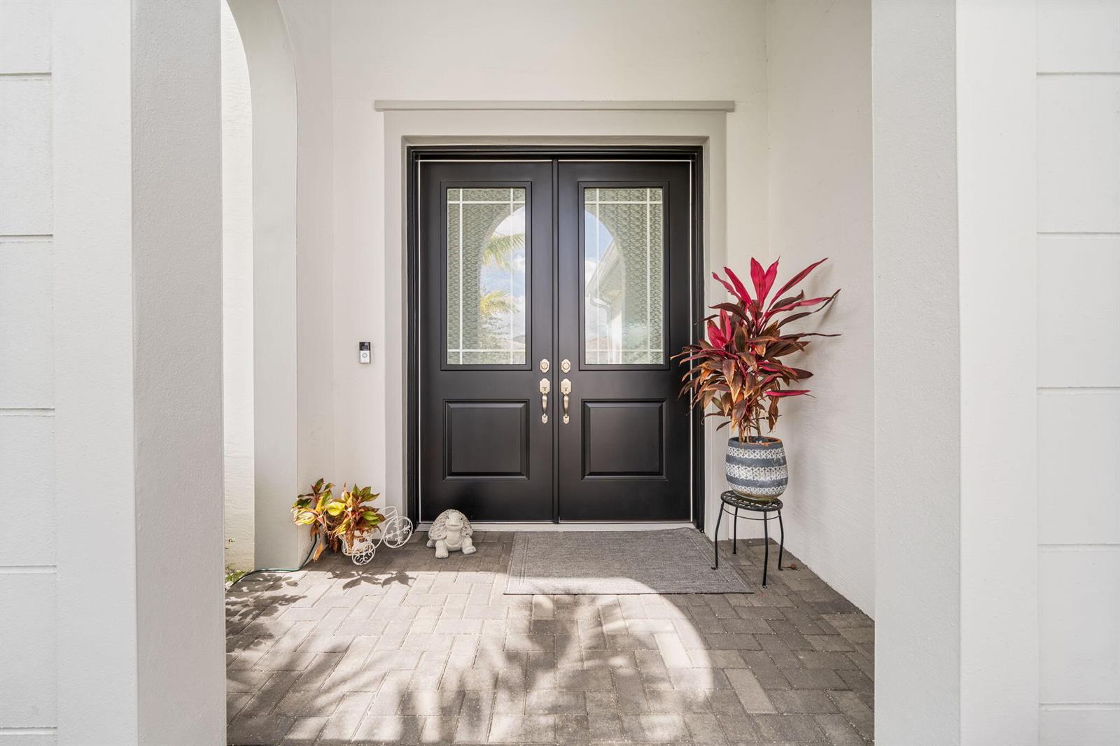 A black double front door with glass panels sits under a white arched entryway — 5449 Empire Drive, Westlake FL 33470, WESTLAKE, FL