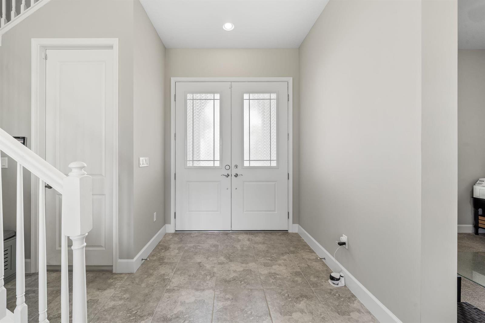 A foyer with tile flooring, a white staircase, and double front doors with glass panels — 5449 Empire Drive, Westlake FL 33470, WESTLAKE, FL