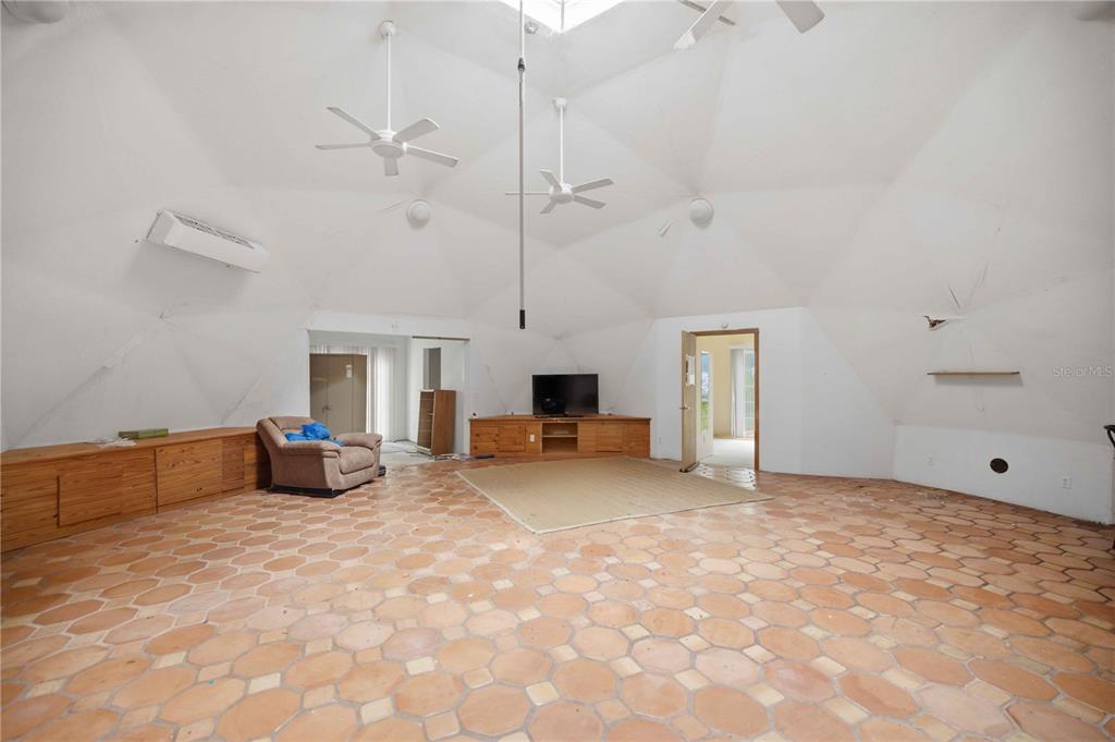 A spacious living room in a geodesic dome house features tiled floors and high ceilings — 12897 NW HIGHWAY 225, REDDICK, FL