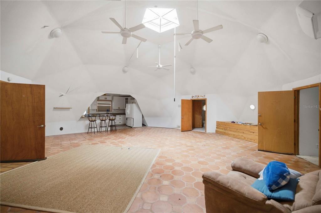 A spacious geodesic dome living area features tiled floors, a central skylight, and an open kitchen — 12897 NW HIGHWAY 225, REDDICK, FL