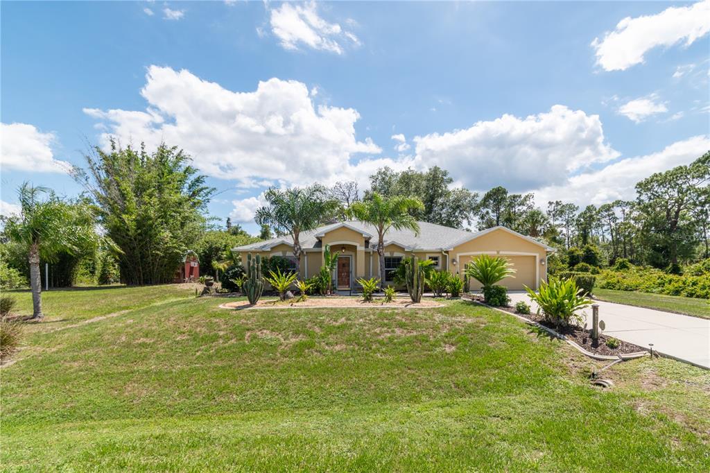 A single-story house with a tan exterior, a two-car garage, and a landscaped front yard — 5769 E PRICE BOULEVARD, NORTH PORT, FL
