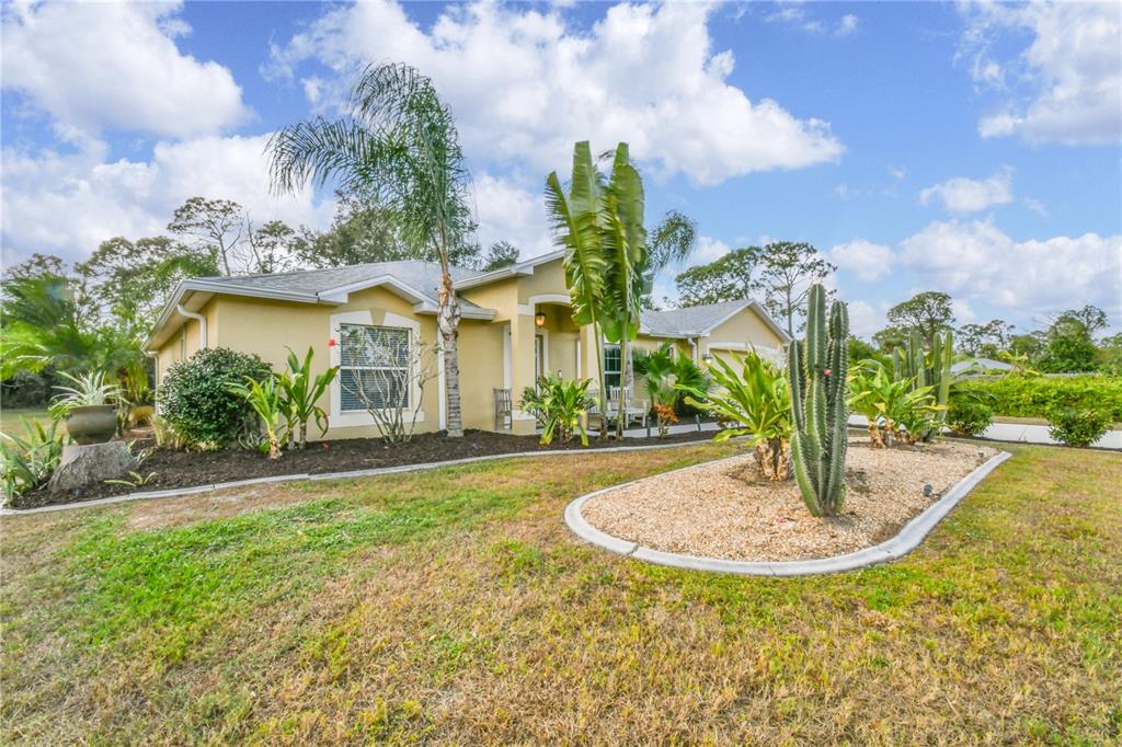 A yellow single-story house features a landscaped front yard with palm trees and cacti — 5769 E PRICE BOULEVARD, NORTH PORT, FL