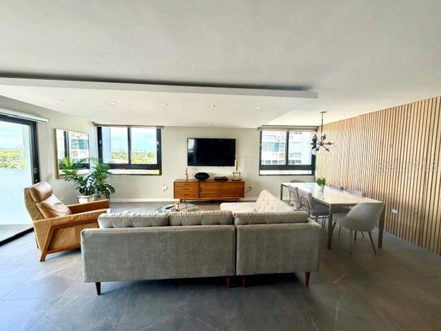 A modern living and dining room features a sectional sofa, wood credenza, and slatted wall — 4123 ISLA VERDE AVENUE UNIT 602, CAROLINA, PR