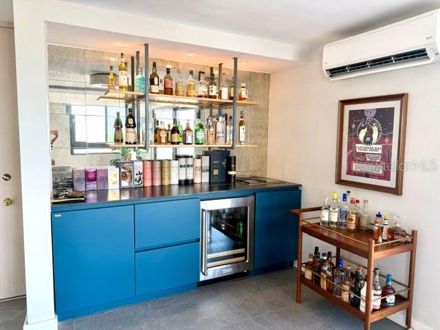 A home bar area features blue cabinetry, open shelving, a wine cooler, and a rolling cart — 4123 ISLA VERDE AVENUE UNIT 602, CAROLINA, PR
