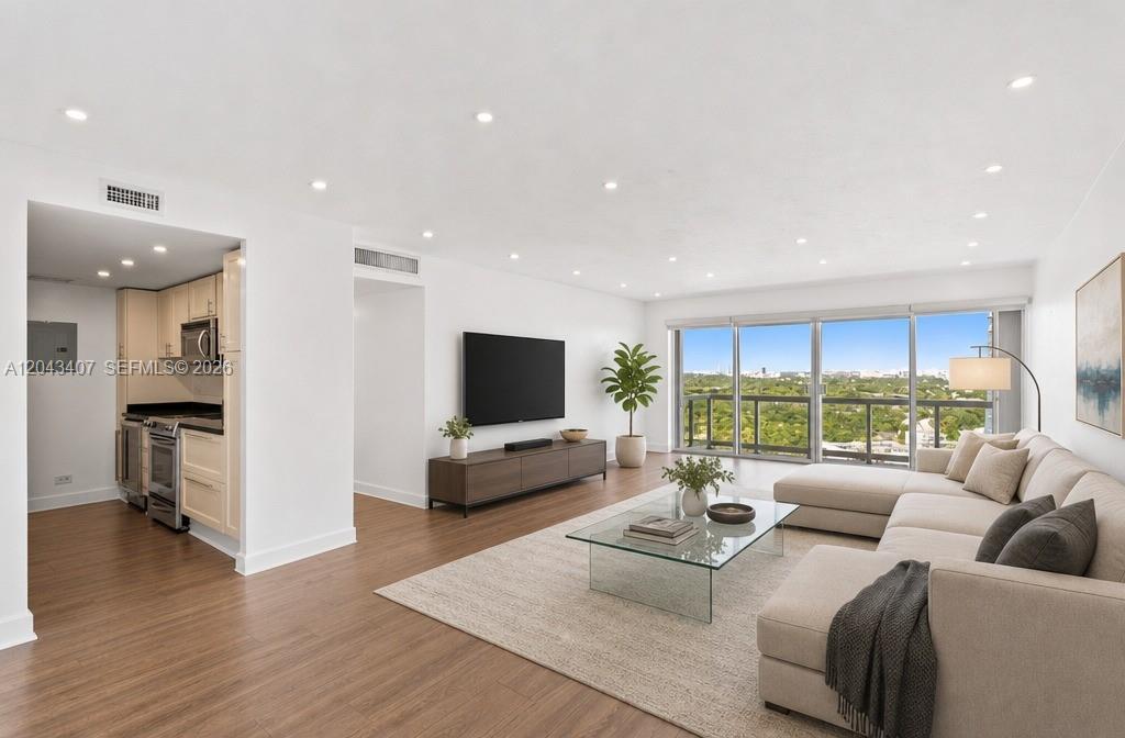 A bright living room features wood flooring, a sectional sofa, and floor-to-ceiling windows — 2451 Brickell Ave, Miami FL 33129, MIAMI, FL
