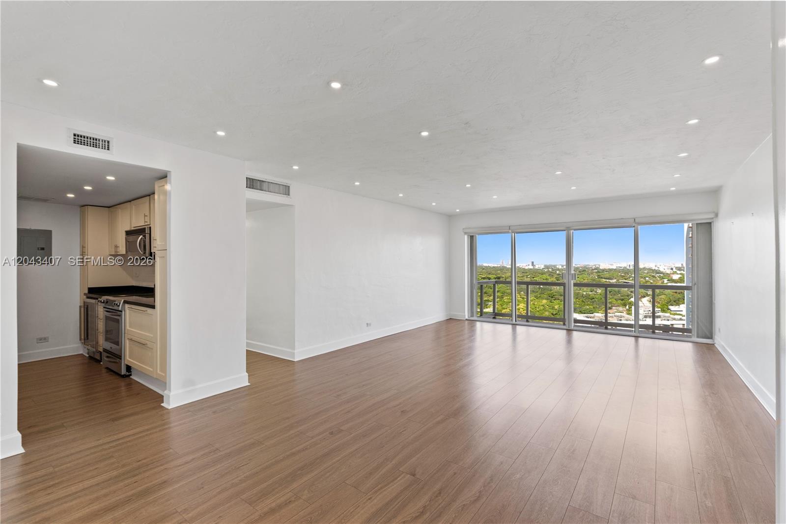 An empty living room with wood-look flooring, recessed lighting, and a balcony with city views — 2451 Brickell Ave, Miami FL 33129, MIAMI, FL