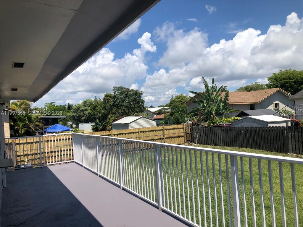 An elevated outdoor balcony with a white railing overlooks a grassy backyard and neighboring houses — 9771 SW 211th st, Cutler Bay FL 33189, CUTLER BAY, FL