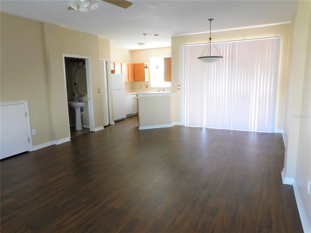 An open-concept living and dining area features dark wood-look flooring and a kitchen beyond — 12450 COUNTRY WHITE CIRCLE, TAMPA, FL