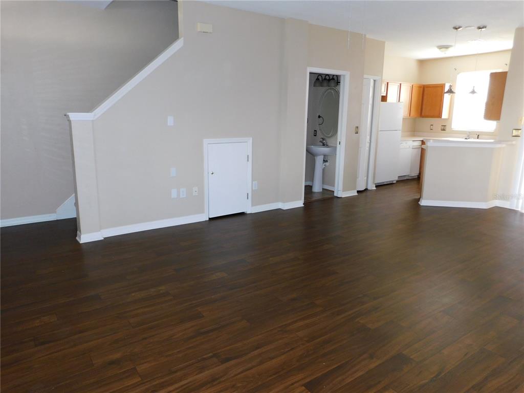 An open-concept living area features dark wood-look flooring, a small storage closet, and a kitchen — 12450 COUNTRY WHITE CIRCLE, TAMPA, FL