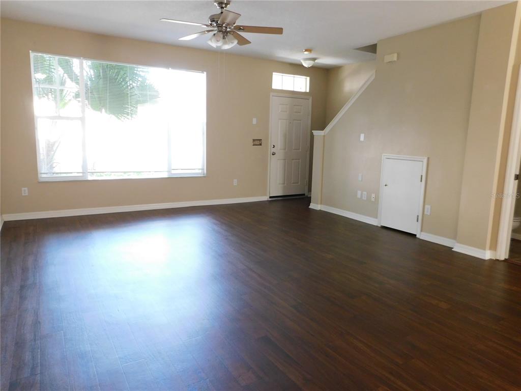 A living room with dark wood flooring, a ceiling fan, and a white front door — 12450 COUNTRY WHITE CIRCLE, TAMPA, FL