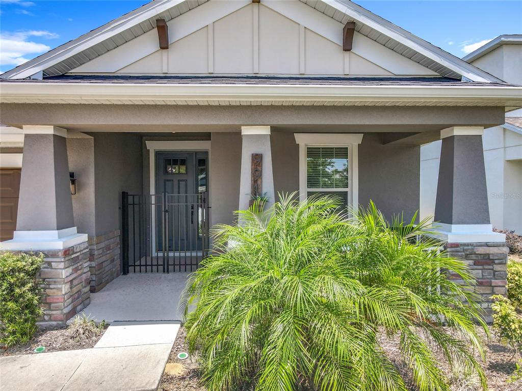 The front exterior of a house features a covered porch with stone-based columns and a palm — 991 LAKESIDE ESTATES DRIVE, APOPKA, FL