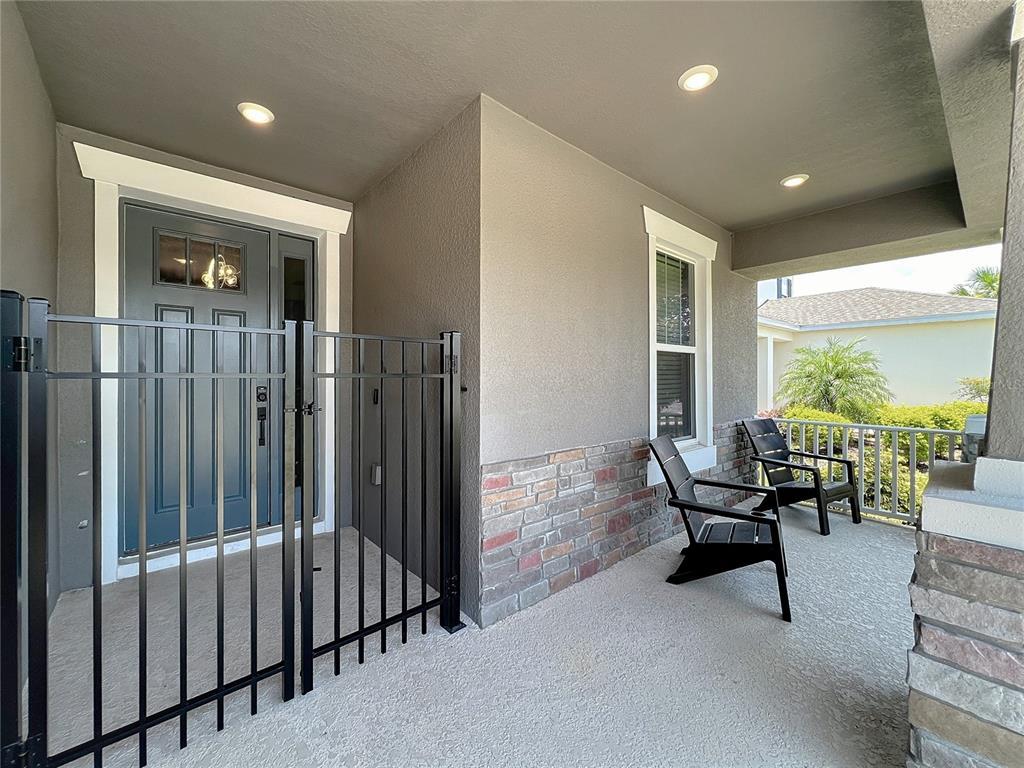 A covered front porch features a gated entryway, stone siding, and two black chairs — 991 LAKESIDE ESTATES DRIVE, APOPKA, FL