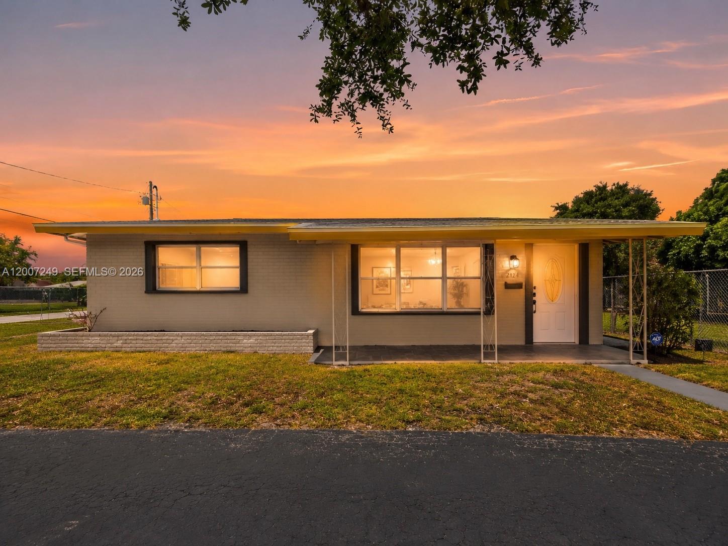 A single-story house with a brick exterior, a covered porch, and a sunset sky — 2724 Acapulco Dr, Miramar FL 33023, MIRAMAR, FL