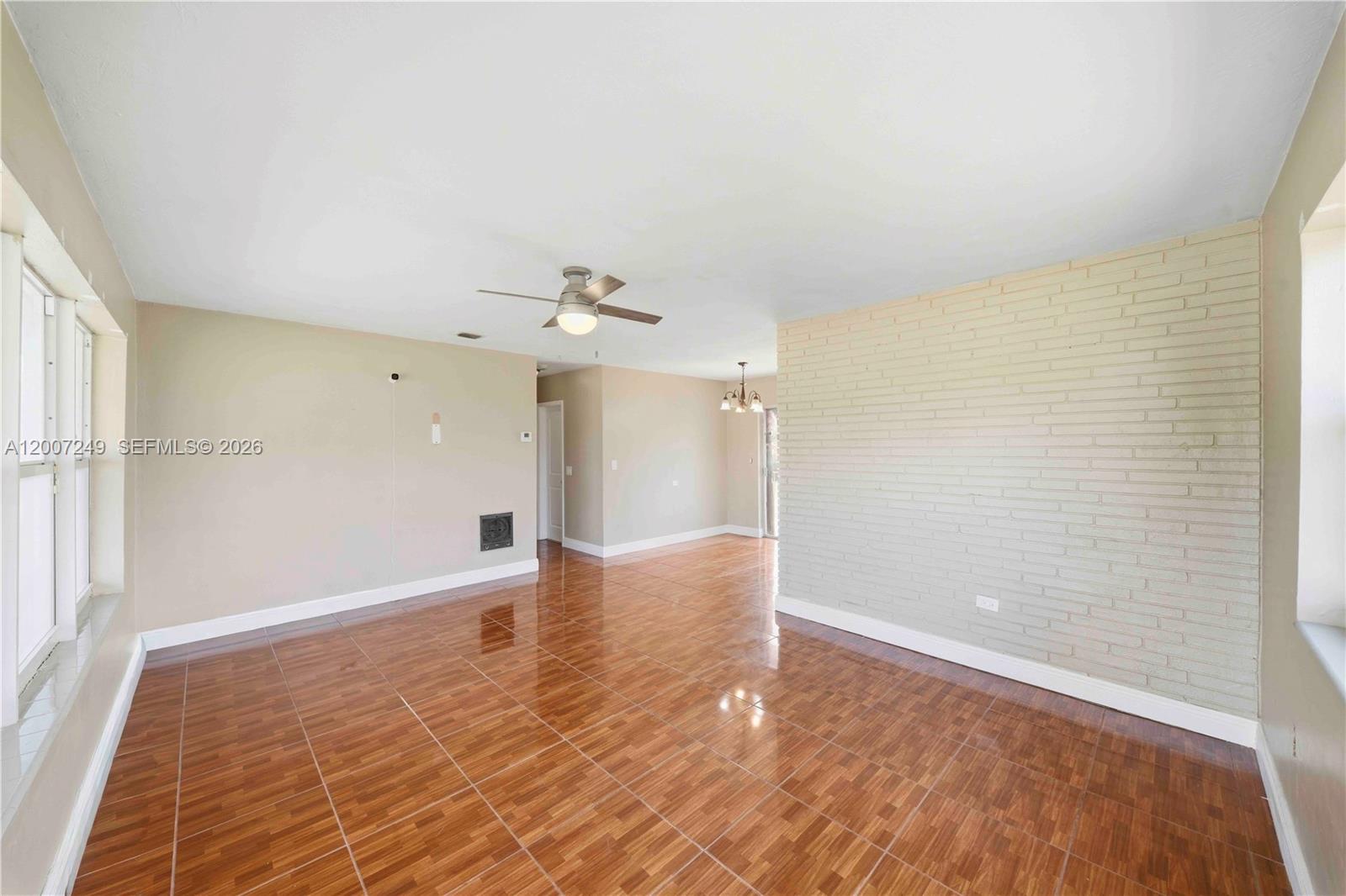 A living room features glossy wood-look tile flooring, a ceiling fan, and a brick wall — 2724 Acapulco Dr, Miramar FL 33023, MIRAMAR, FL