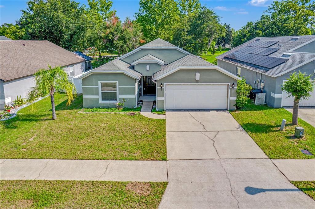 The exterior of a house features a green stucco facade, a dark front door, and a walkway — 605 SWAN RANGE ROAD, ORANGE CITY, FL