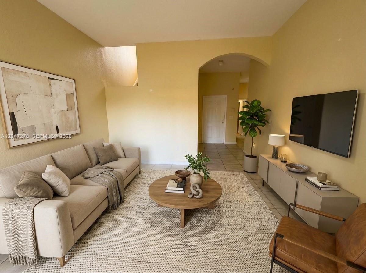 A living room features a beige sofa, a round wooden coffee table, and a television — 2363 SE 19th St, Homestead FL 33035, HOMESTEAD, FL