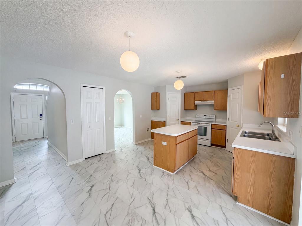 A kitchen with wood cabinets, a center island, and white marble-patterned tile flooring — 5191 QUINTILIS STREET, SPRING HILL, FL