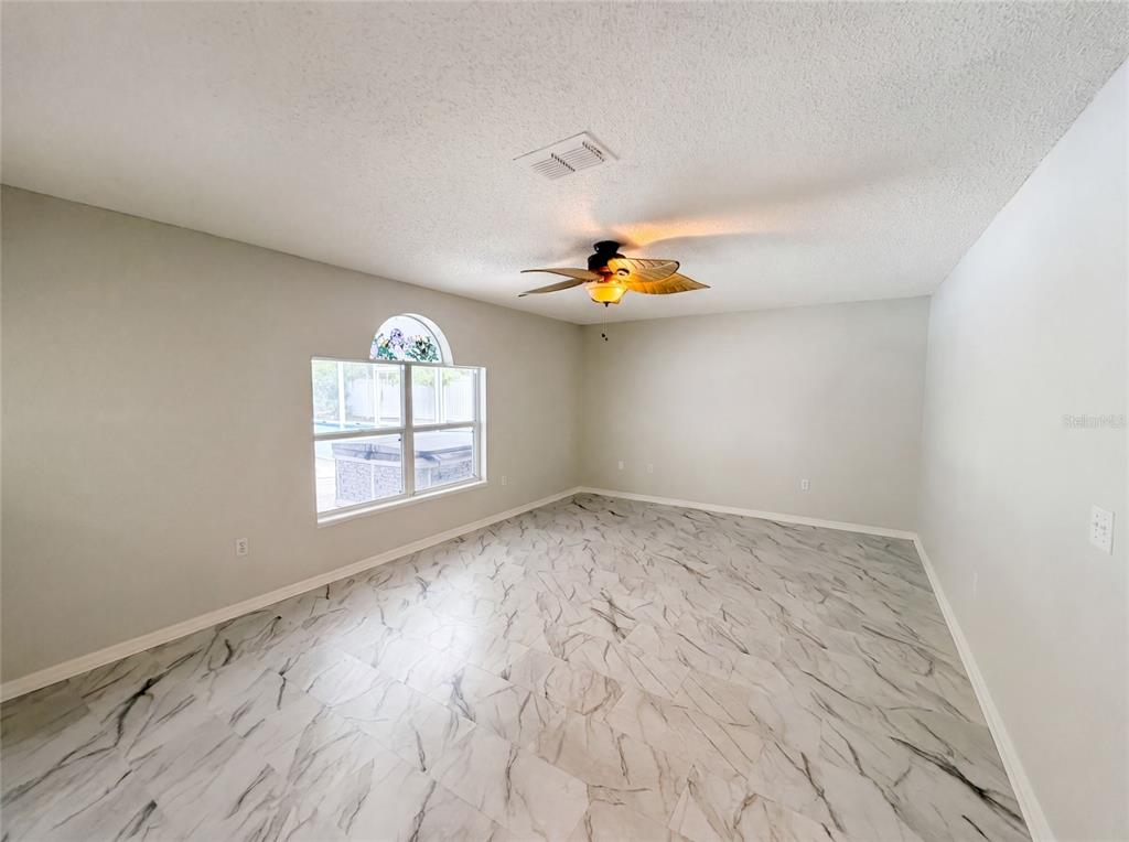 An empty room with light gray walls, white marble-patterned tile floors, and a ceiling fan — 5191 QUINTILIS STREET, SPRING HILL, FL