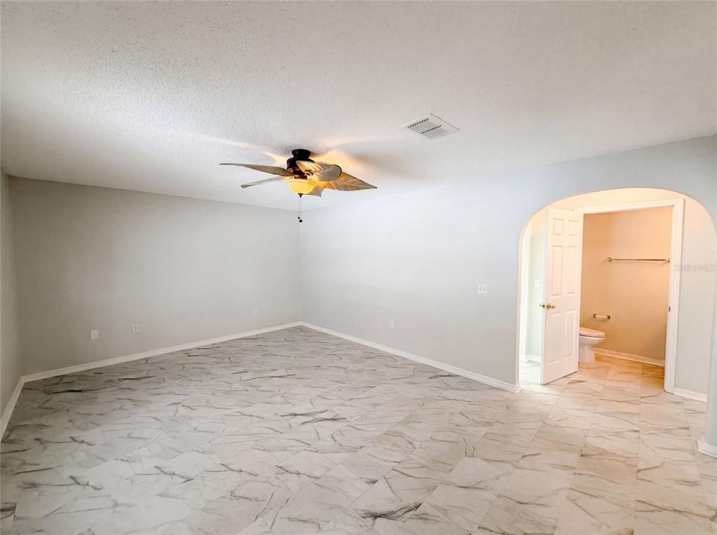 A room with light gray walls, a ceiling fan, and white marble-patterned tile flooring — 5191 QUINTILIS STREET, SPRING HILL, FL