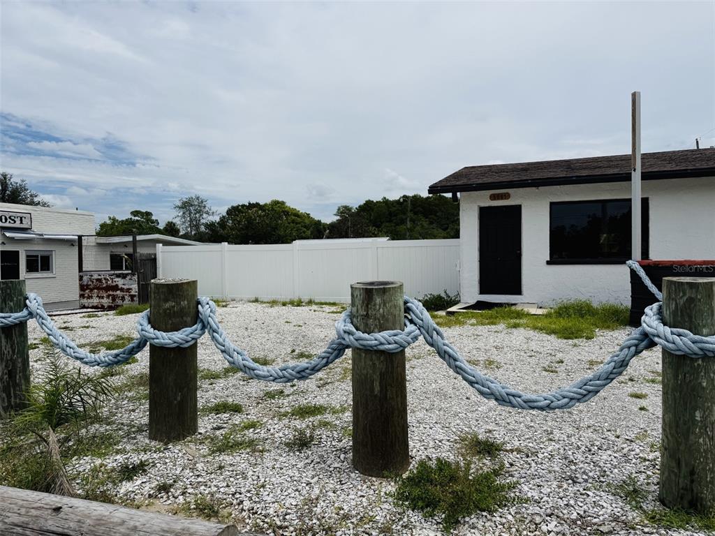 A gravel lot features wooden posts connected by thick blue rope in front of buildings — 8061 CORTEZ BOULEVARD, WEEKI WACHEE, FL