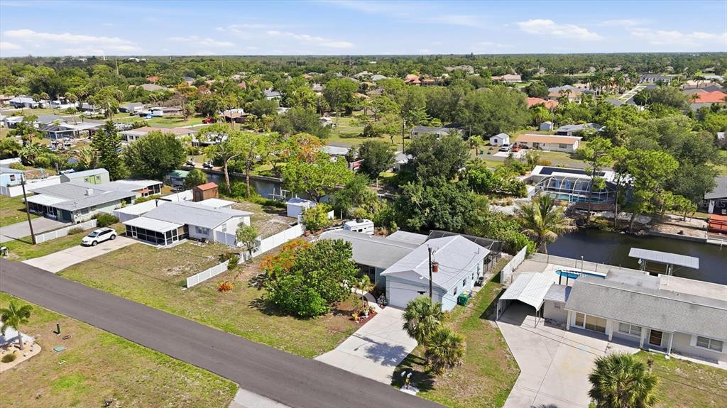 An aerial view shows several single-story houses with driveways and yards near a canal — 852 E 6TH STREET, ENGLEWOOD, FL