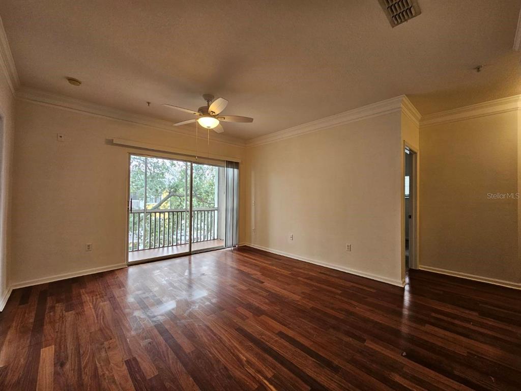 An empty living room features hardwood floors, a ceiling fan, and a sliding glass door — 4207 S DALE MABRY HIGHWAY UNIT 10310, TAMPA, FL