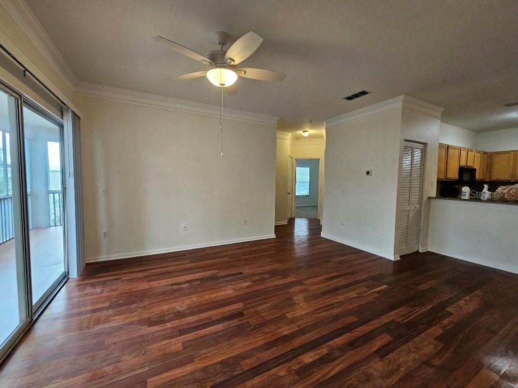 An open-concept living area features dark wood-look flooring, a ceiling fan, and a kitchen view — 4207 S DALE MABRY HIGHWAY UNIT 10310, TAMPA, FL