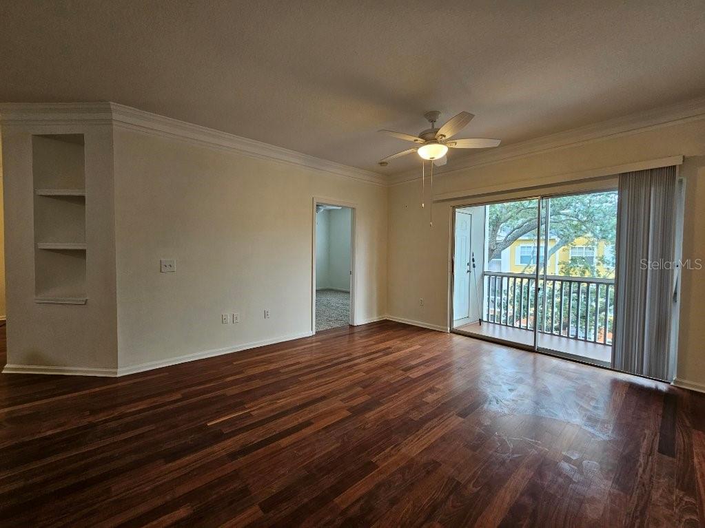 An empty living room features wood-look flooring, a ceiling fan, and a sliding glass door — 4207 S DALE MABRY HIGHWAY UNIT 10310, TAMPA, FL