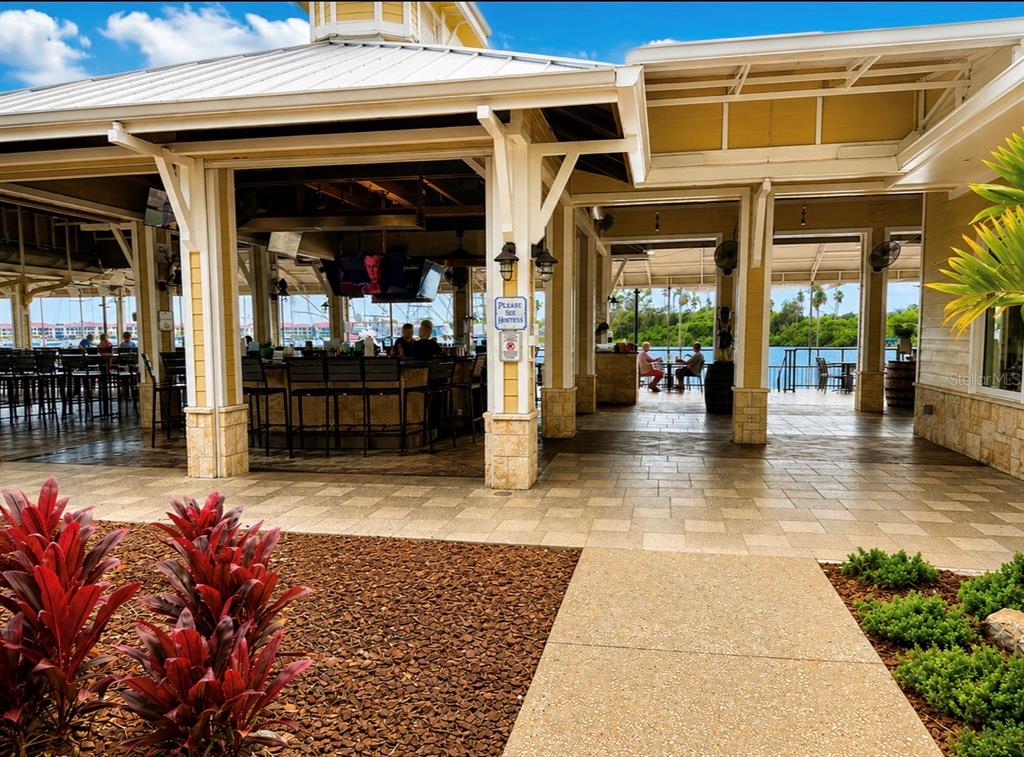 An open-air waterfront bar and restaurant features a tiled patio, bar seating, and outdoor tables — 100 BOAT YARD STREET UNIT D10, NEW SMYRNA BEACH, FL