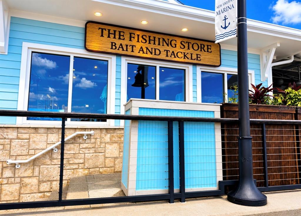 The exterior of a light blue building features a sign reading The Fishing Store — 100 BOAT YARD STREET UNIT D10, NEW SMYRNA BEACH, FL