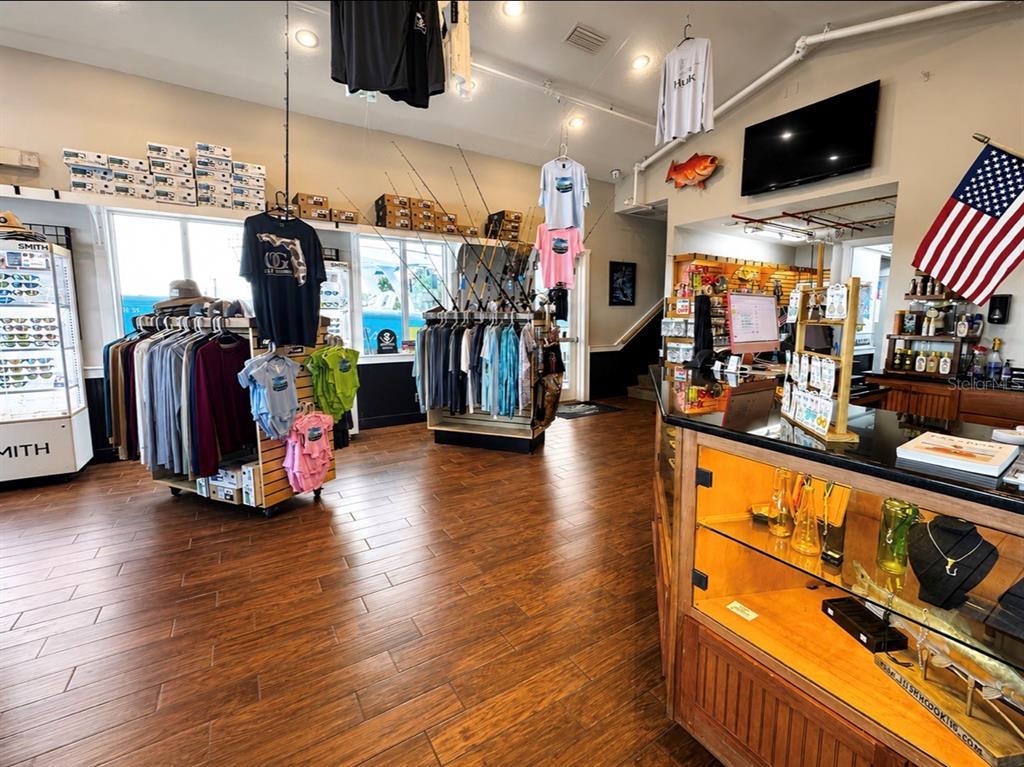 A retail store features wood-look flooring, clothing racks, fishing gear, and a glass display counter — 100 BOAT YARD STREET UNIT D10, NEW SMYRNA BEACH, FL
