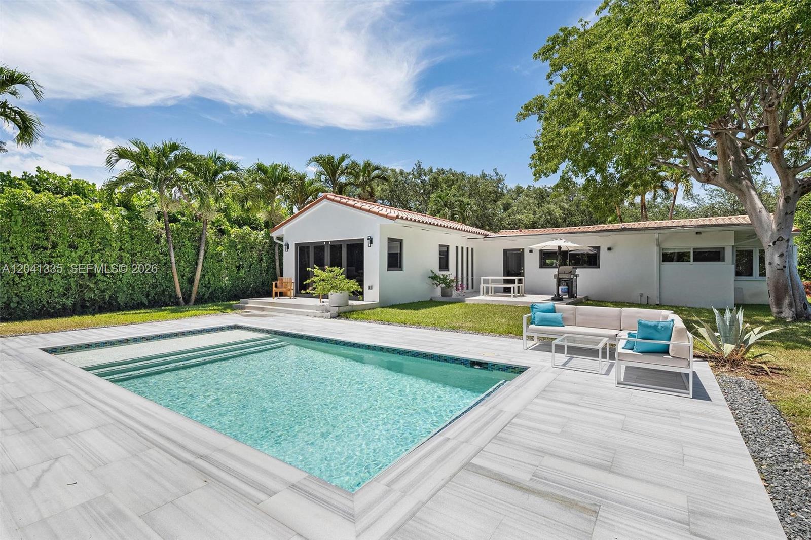 A backyard features a rectangular swimming pool, a white patio, and a single-story house — 360 NE 91st St, Miami Shores FL 33138, MIAMI SHORES, FL