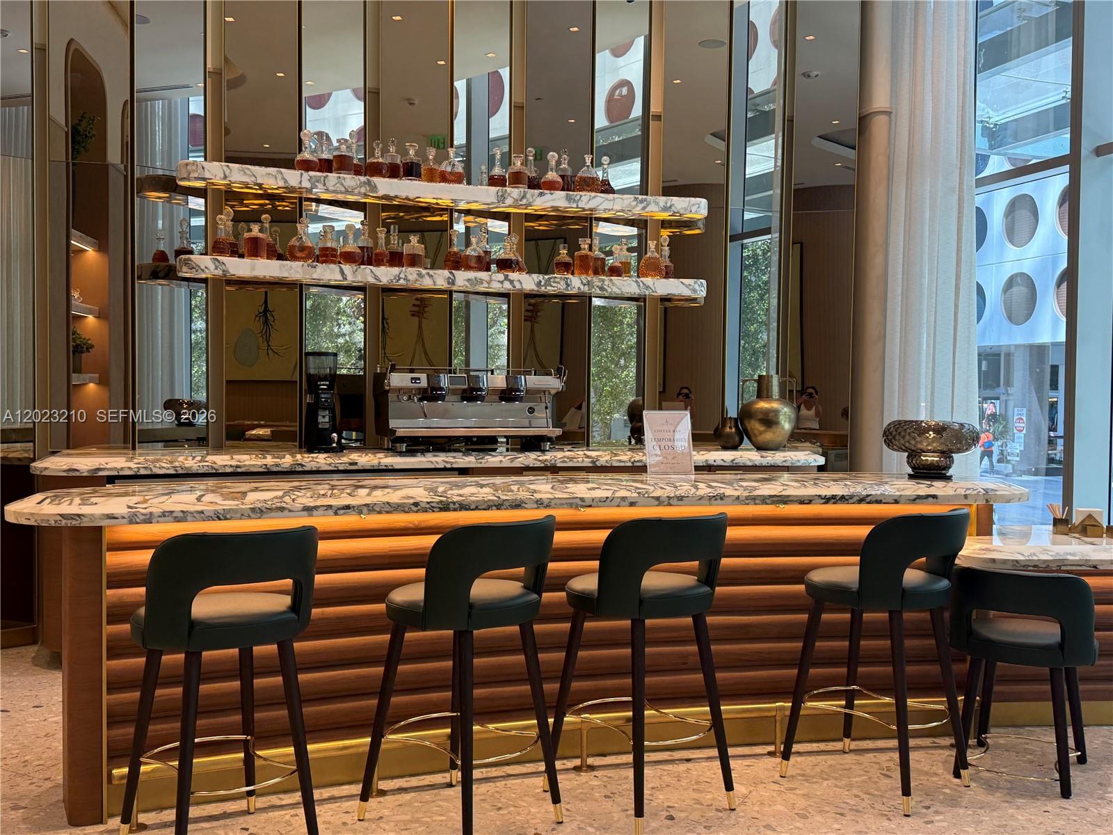 A bar area features a marble counter, dark stools, and illuminated glass shelves with decanters — 77 SE 5th ST # 2111, Miami FL 33131, MIAMI, FL