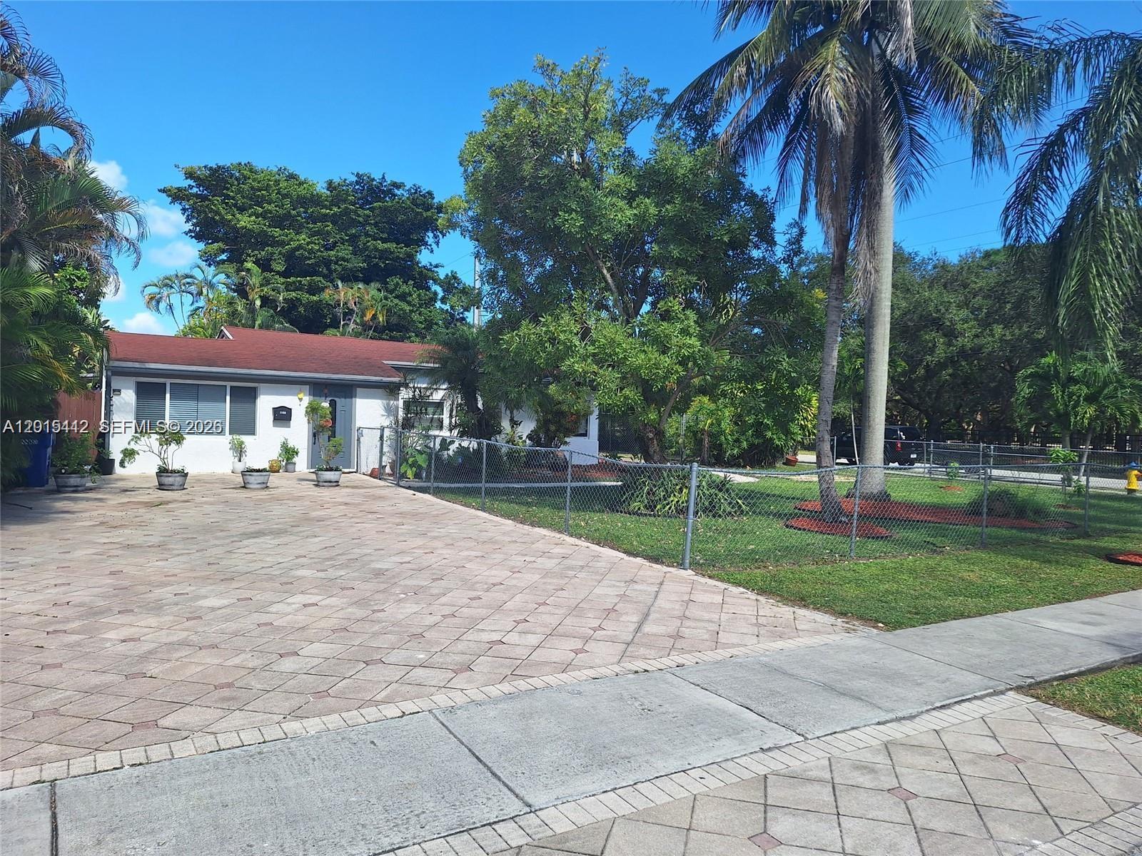 A single-story house with a paved driveway, a chain-link fence, and mature palm trees — 2199 NE 182nd St # 0, North Miami Beach FL 33162, NORTH MIAMI BEACH, FL