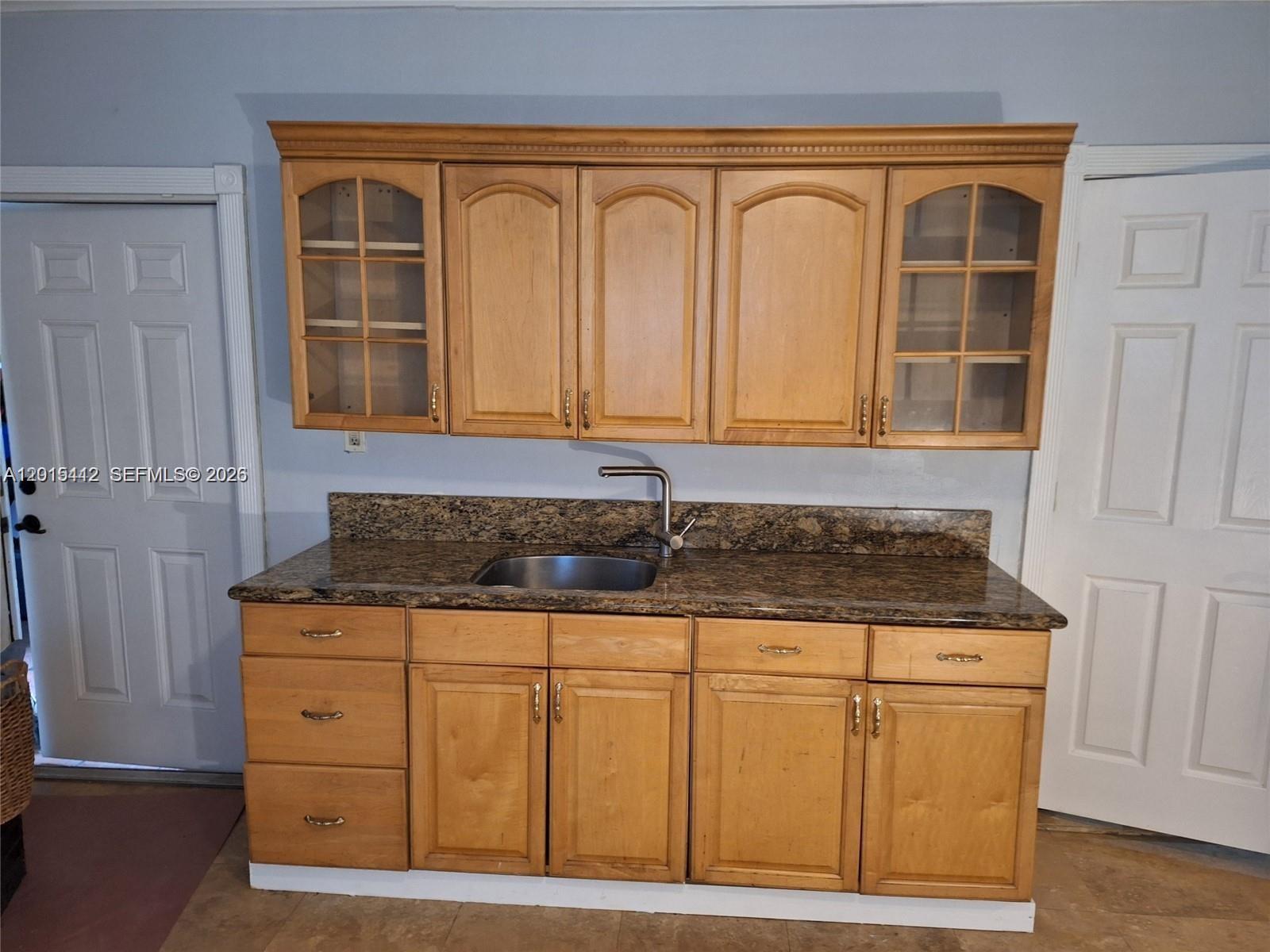 A kitchen wet bar features light wood cabinets, a granite countertop, and a stainless sink — 2199 NE 182nd St # 0, North Miami Beach FL 33162, NORTH MIAMI BEACH, FL