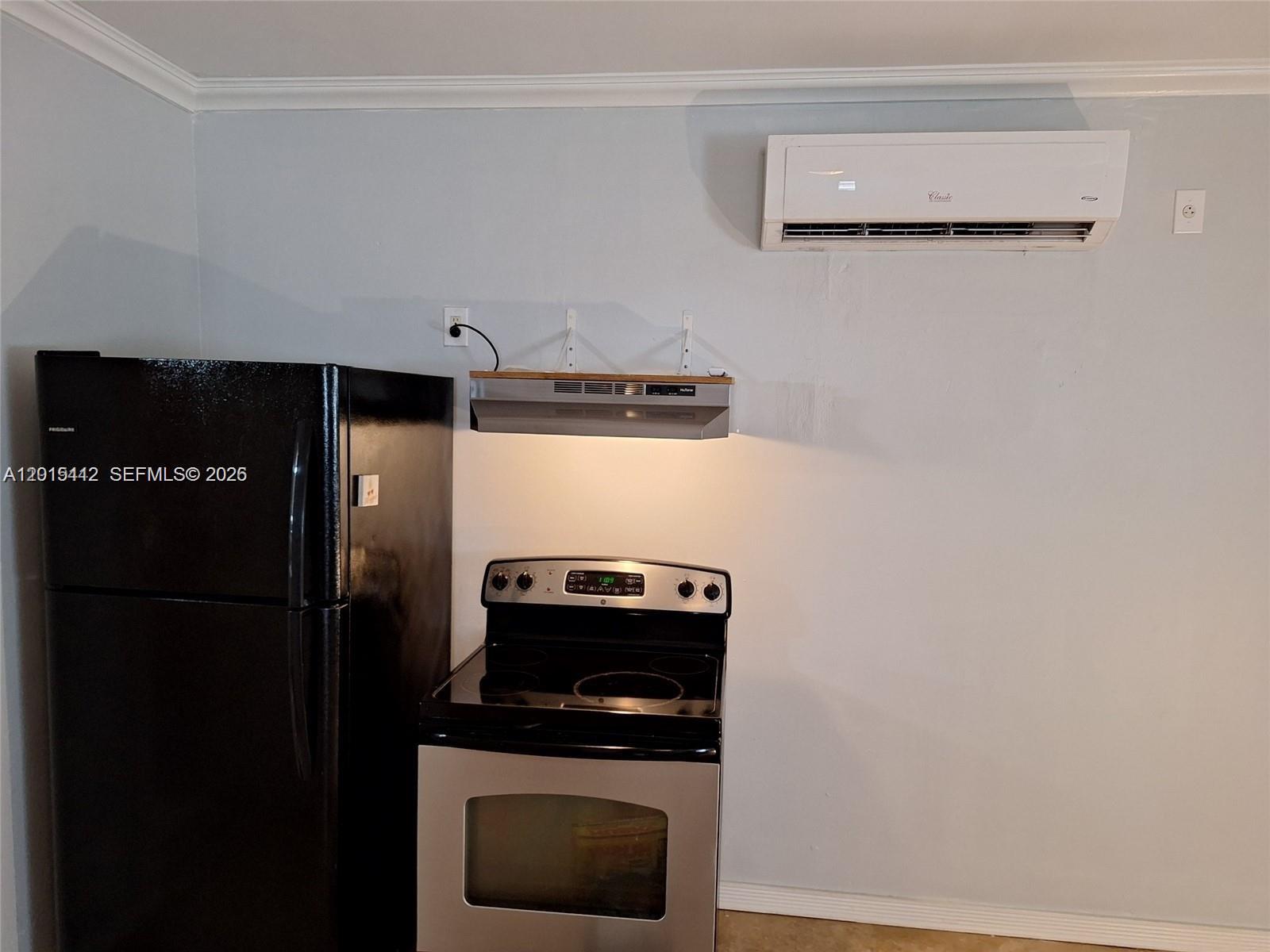 A kitchen area features a black refrigerator, a stainless steel stove, and a wall-mounted air conditioner — 2199 NE 182nd St # 0, North Miami Beach FL 33162, NORTH MIAMI BEACH, FL