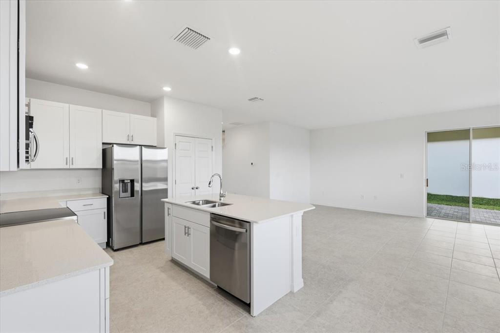 A modern kitchen features white cabinets, stainless steel appliances, a center island, and tile flooring — 167 BOTTLE BRUSH DRIVE, HAINES CITY, FL